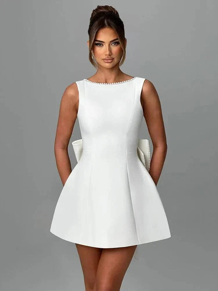 Vestido Mini branco em tecido crepe com corte evasê, cintura alta marcada e detalhe de pérolas no decote canoa