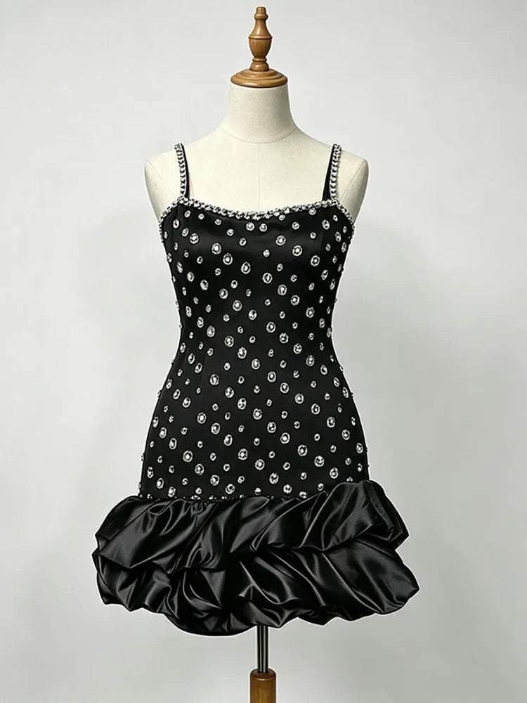 Vestido preto justo com alças finas, decorado com cristais prateados e bainha volumosa de folhos em cetim