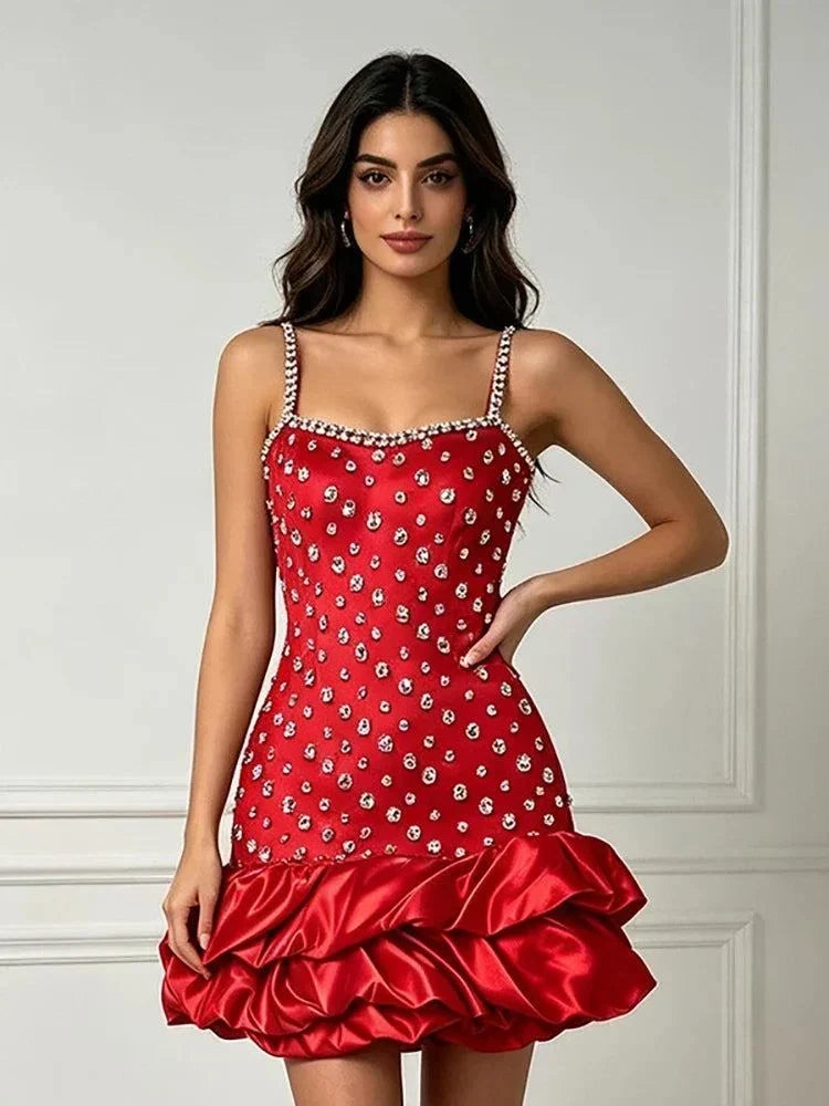 Vestido vermelho justo com alças finas e aplicações brilhantes, decote direito e bainha volumosa de folhos acetinados