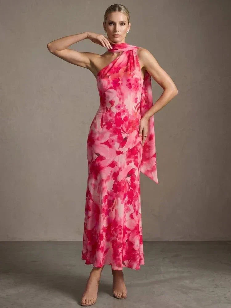 Vestido longo floral rosa com gola assimétrica e echarpe fluida, ideal para eventos elegantes e verão.