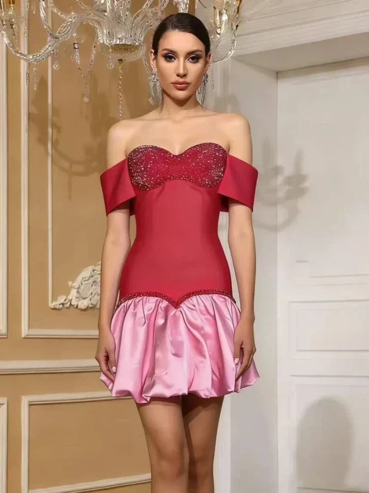 Vestido mini de bandagem vermelho e rosa com ombros descobertos e decote coração com pedraria brilhante.
