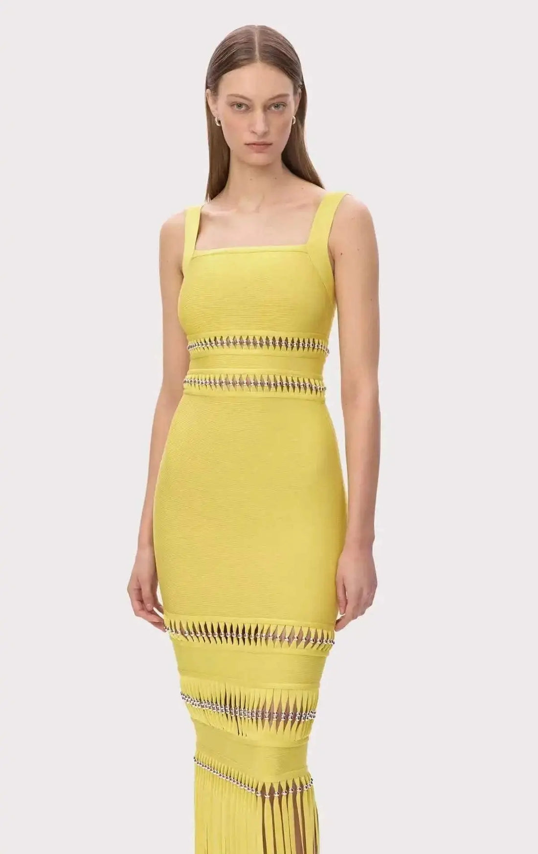 Vestido Bandagem amarelo sem mangas, justo, com decote quadrado, faixas vazadas e franjas compridas na bainha.