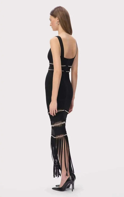 Vestido Bandagem preto e justo, sem mangas, com tiras decorativas prateadas e longas franjas na bainha.