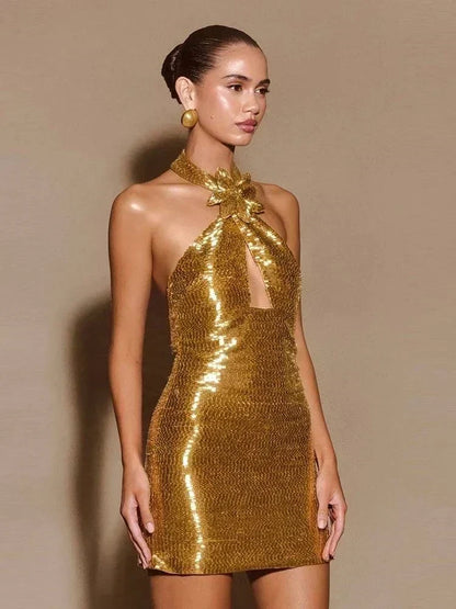 Vestido Flor de Ouro mini dourado, justo e coberto de lantejoulas, com gola frente única e flor decorativa no pescoço