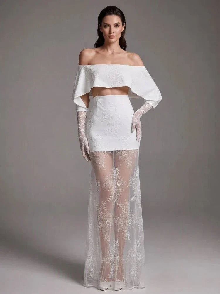 Vestido Nobreza branco-mar fim, com capa drapeada sem ombros, saia curta estruturada e sobressaia longa de renda floral translúcida, acompanhado por luvas compridas.