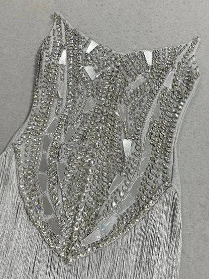 Vestido prateado com corpete bordado de cristais e aplicações espelhadas geométricas, terminado em franjas compridas