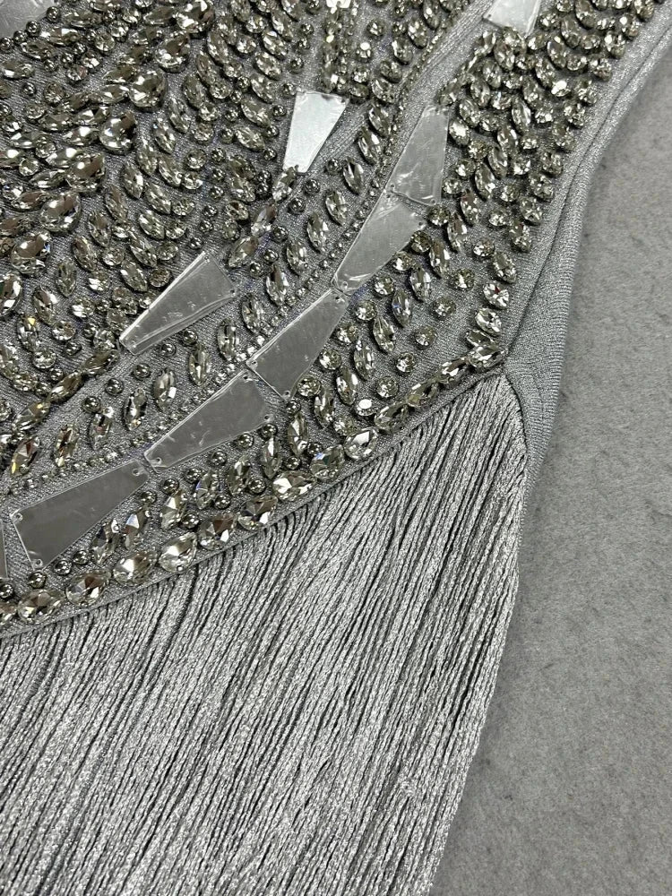 Vestido prateado com corpete bordado de cristais e aplicações espelhadas geométricas, adornado com franjas brilhantes