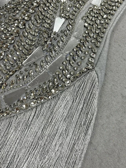 Vestido prateado com corpete bordado de cristais e aplicações espelhadas geométricas, adornado com franjas brilhantes