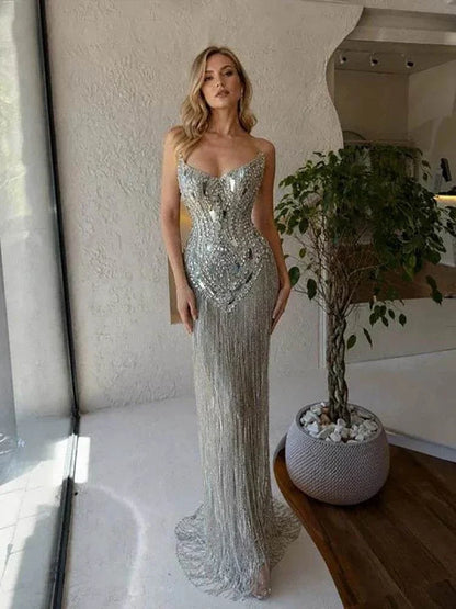 Vestido comprido prateado com corpete de alças finas coberto de cristais e saia de franjas brilhantes até ao chão