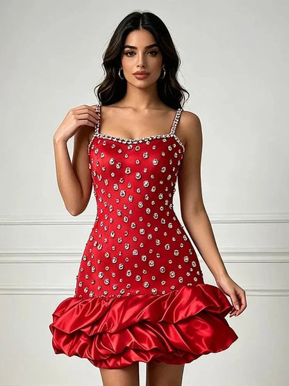 Vestido vermelho de alças finas, bordado com cristais em padrão simétrico e saia curta com babados volumosos de cetim.